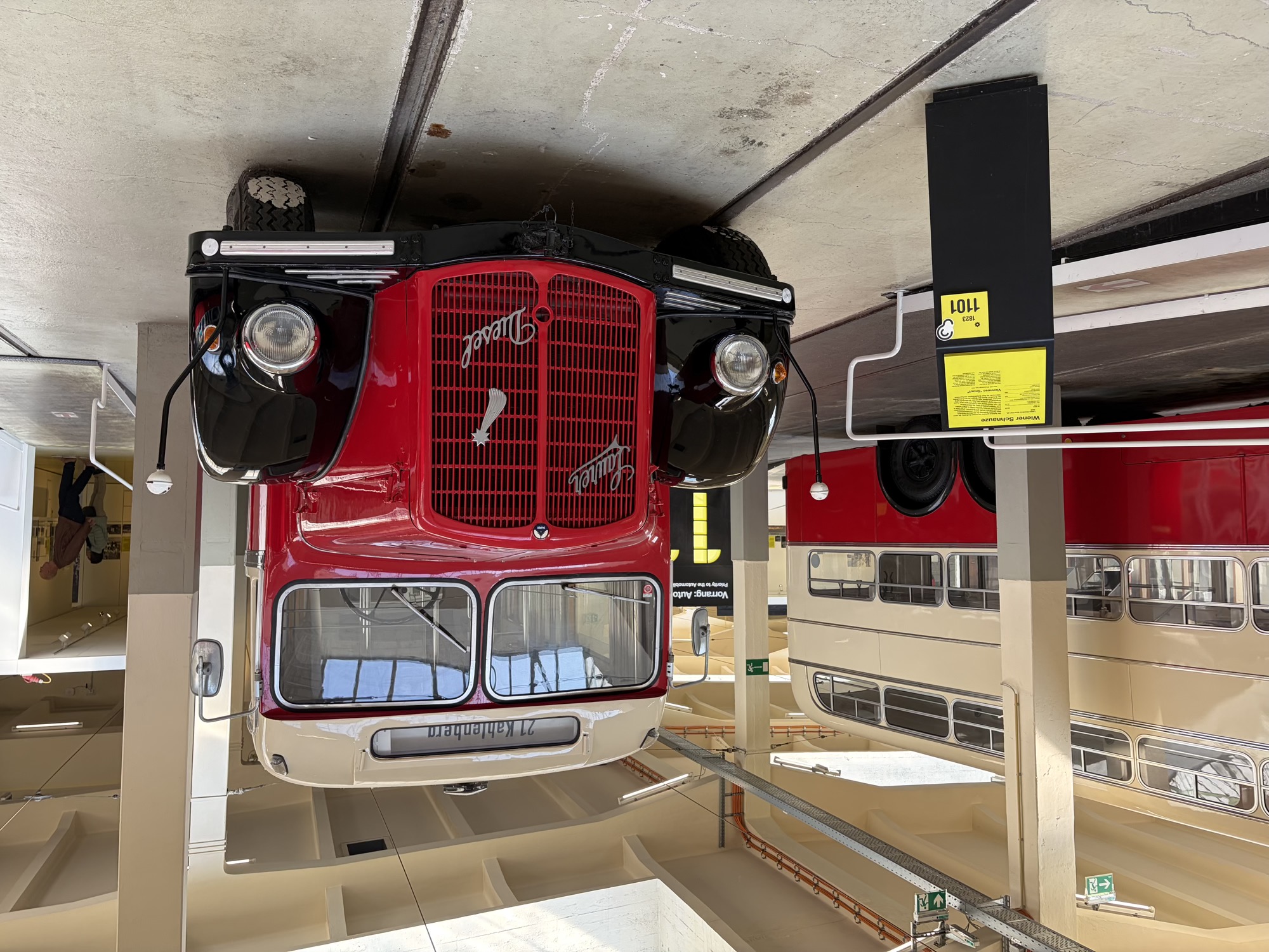Oldtimer-Autobus mit der Zieltafel „21 Kahlenberg“ über der zweigeteilten Windschutzscheibe, die Motorhaube ist rot gestrichen, am Kühlergrill sind neben dem Symbol einer Sternschnuppe in geschwungener Schrift die beiden Worte „Saurer Diesel“ zu sehen, auf den schwarz gestrichenen Radverkleidungen sind die Scheinwerfer befestigt, links und rechts ragen zwei „Antennen“ mit weißen Kugelköpfen zur Seite